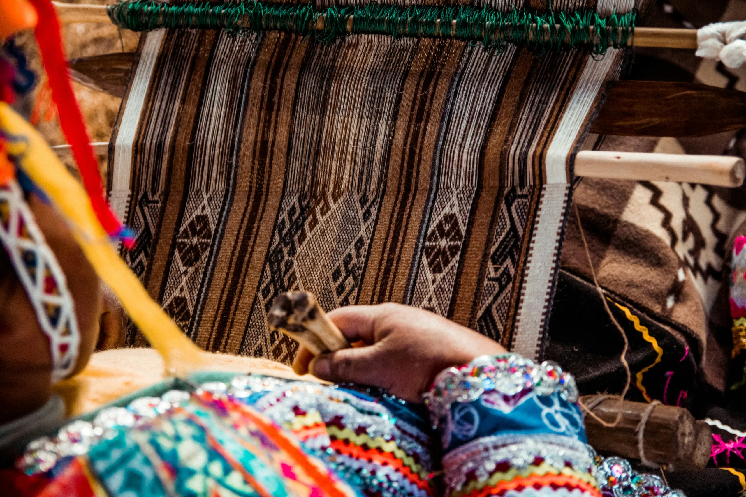 Artisanat traditionnel au Pérou : main d’une femme andine tissant un textile sur un métier à tisser, élément culturel fort à valoriser dans un travel planner péruvien axé sur les savoir-faire locaux.