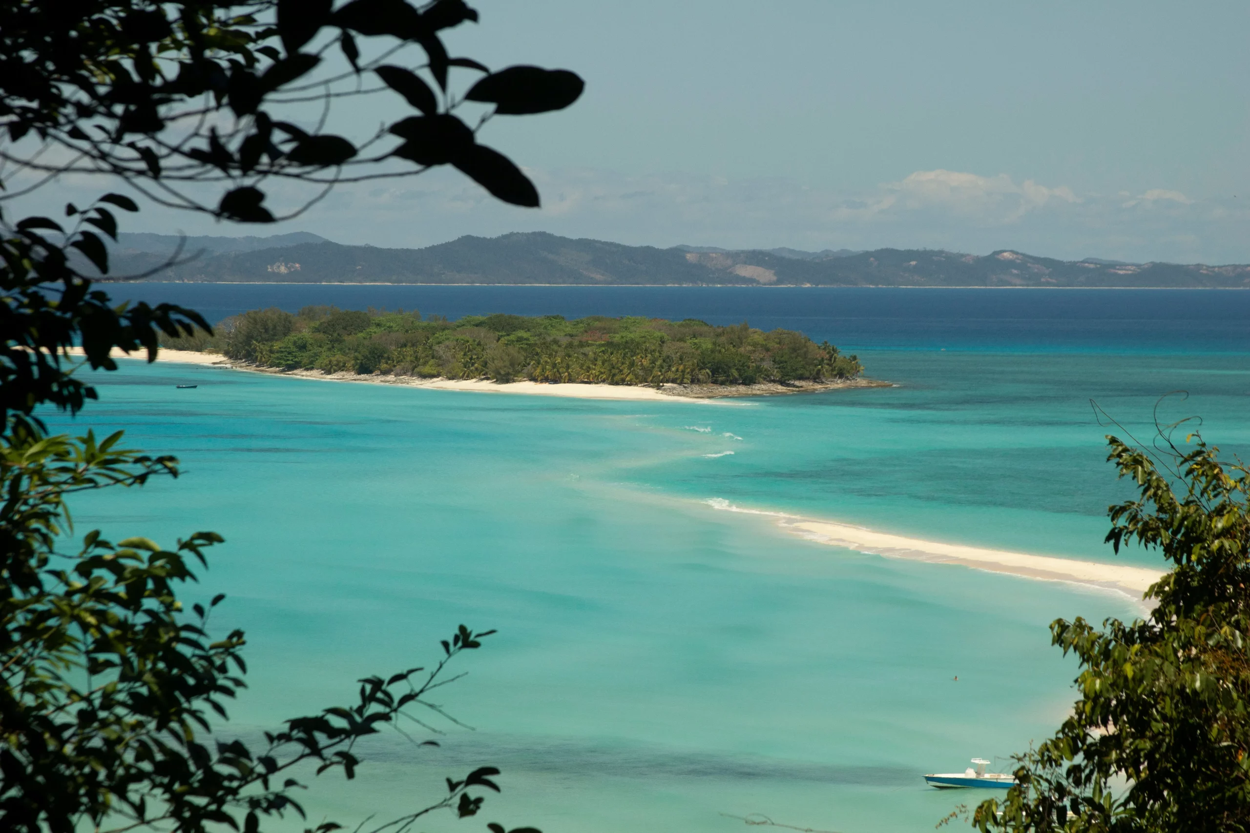 Plage de sable blanc bordée par une mer turquoise à Madagascar, paysage paradisiaque idéal pour le tourisme balnéaire.