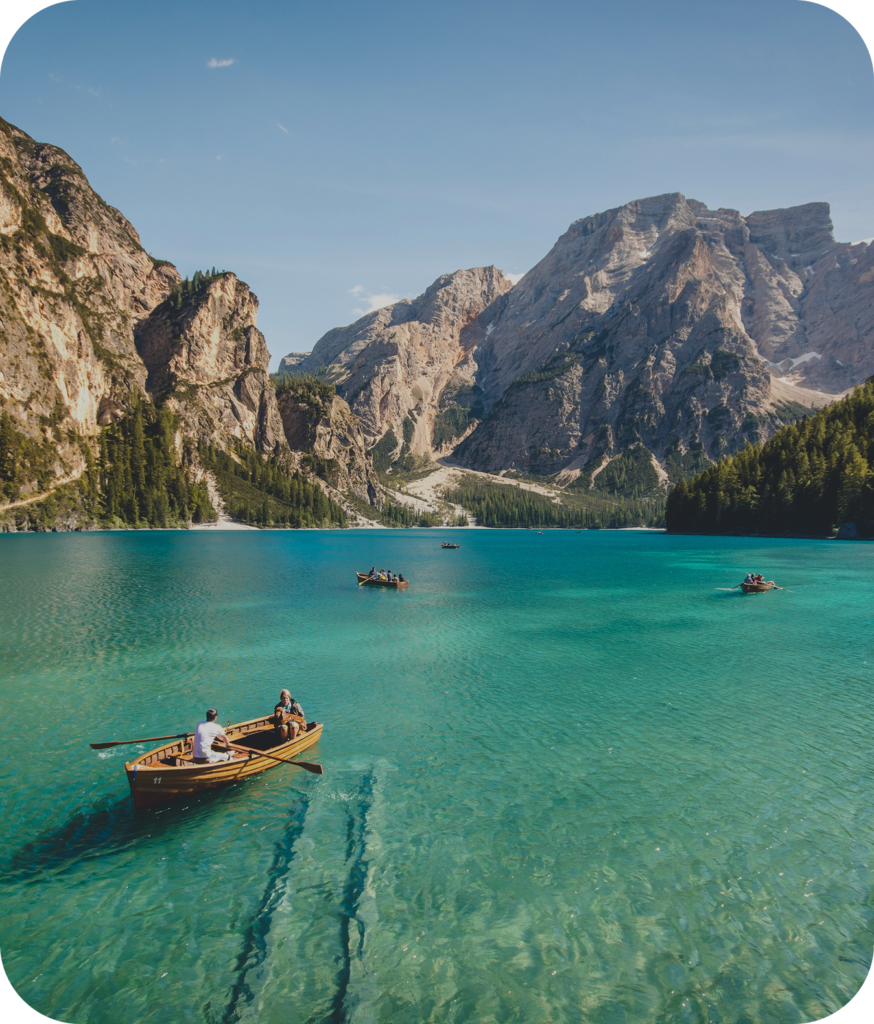Balade en barque sur un lac alpin aux eaux turquoise entouré de montagnes majestueuses, une expérience nature conçue par un travel planner pour un séjour paisible et dépaysant.