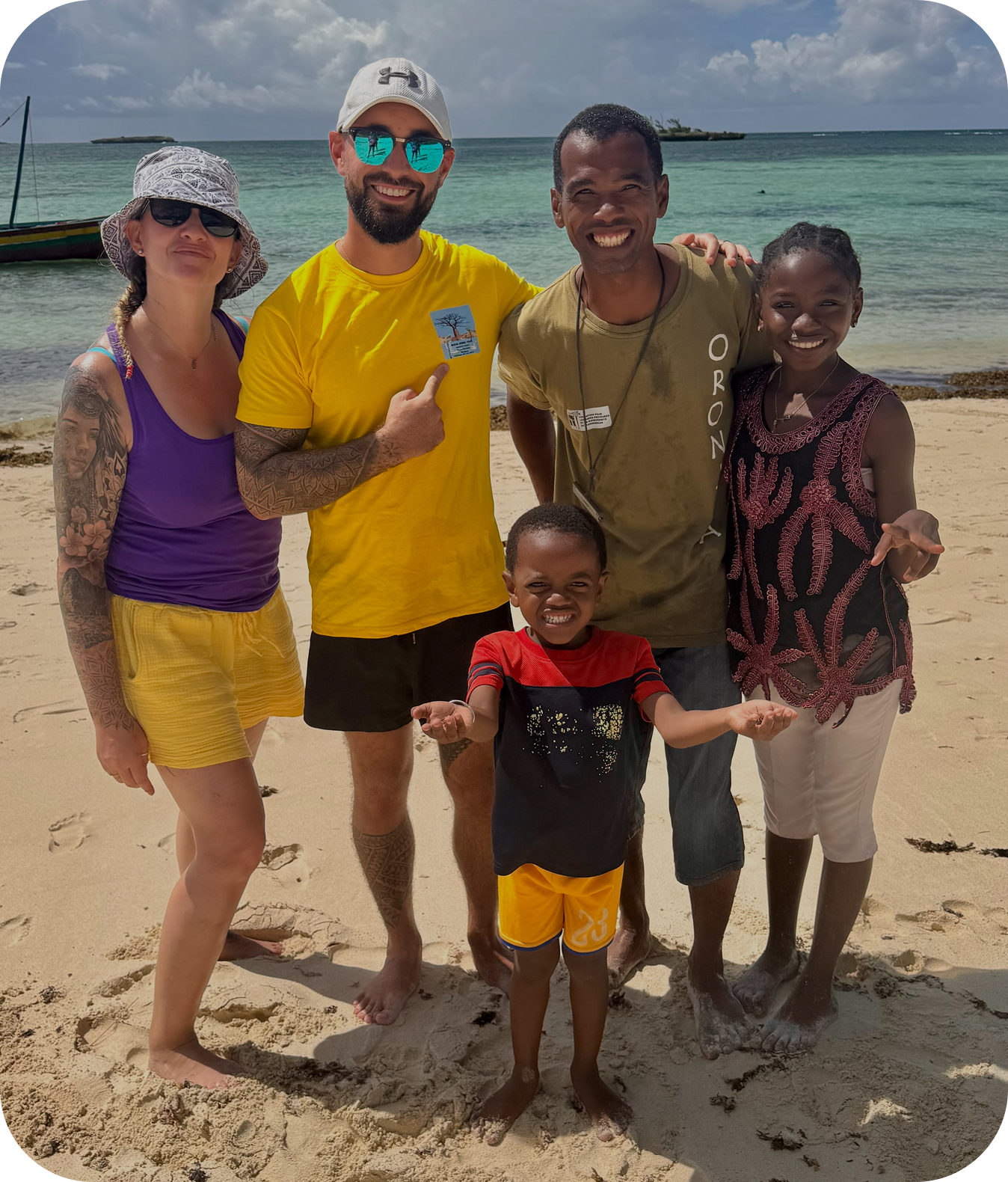 July, travel planner de Globe Shard, partage un moment convivial avec une famille locale sur une plage de sable fin à Madagascar, symbole d’un voyage solidaire et authentique.