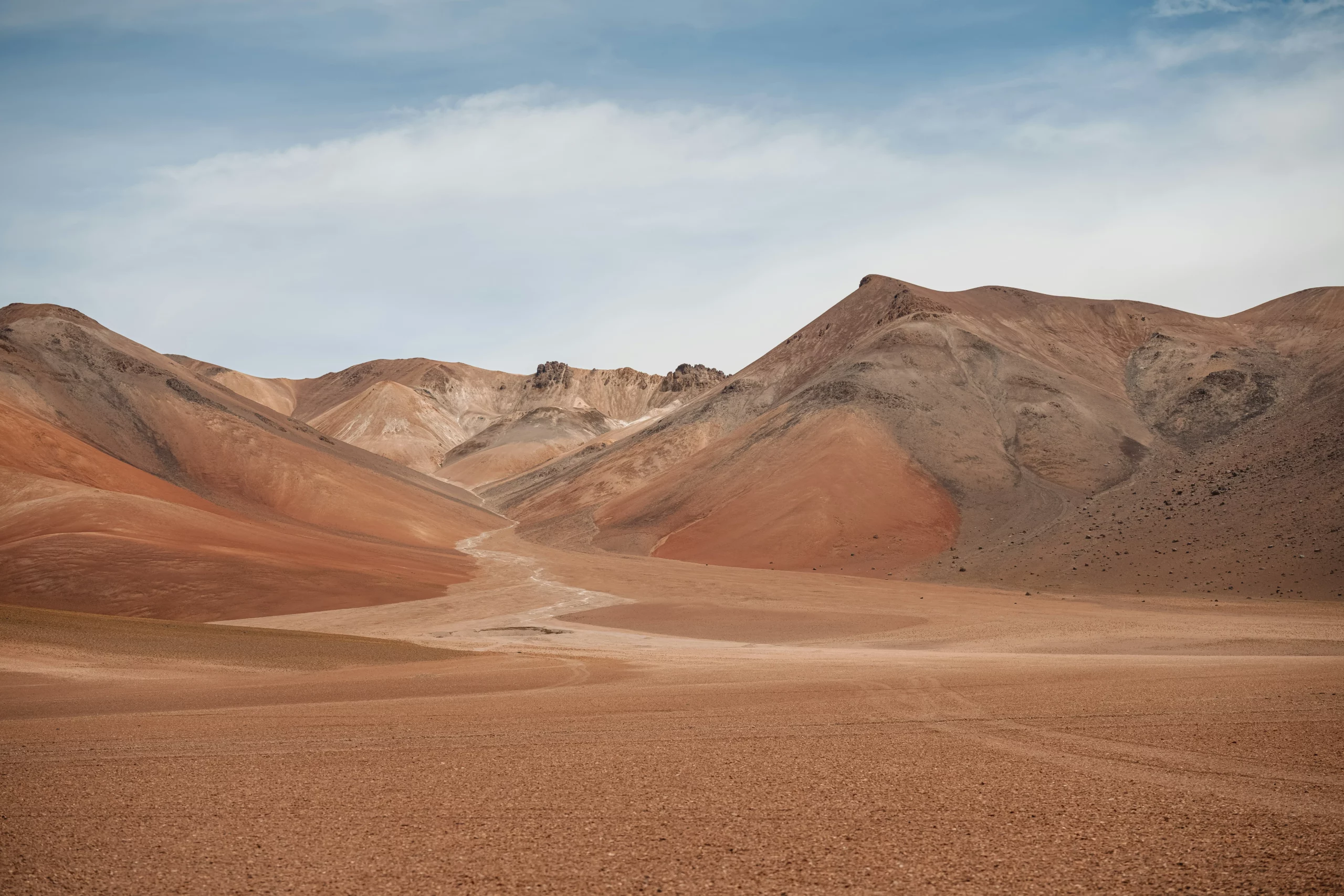 Paysage aride du désert de Siloli en olivie, aux montagnes ocres et ciel clair, site spectaculaire à inclure dans un travel planner Bolivie pour les amoureux de grands espaces sauvages.