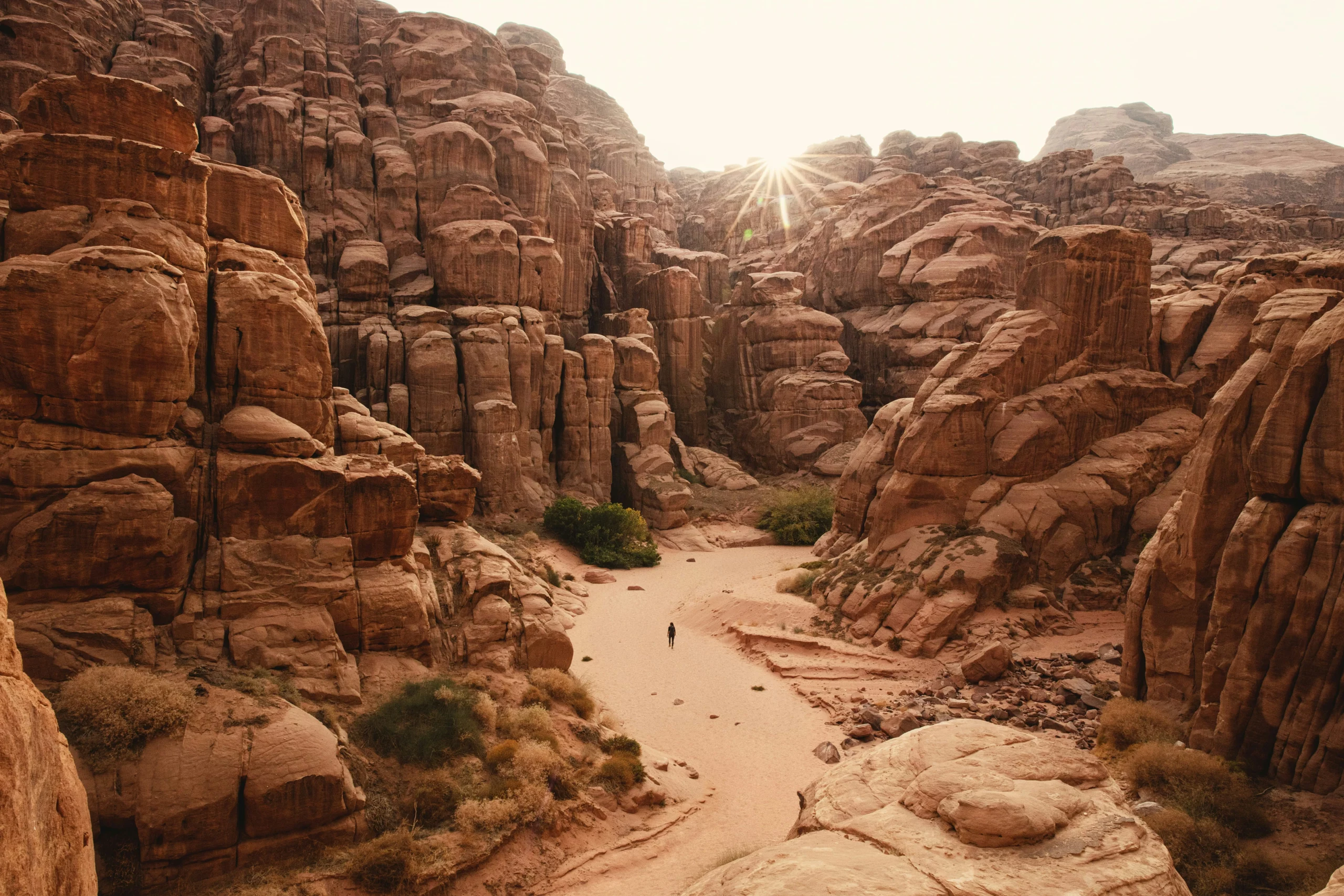 Sentier dans un canyon désertique avec formations rocheuses rougeoyantes, symbolisant les paysages emblématiques du Sud-Ouest américain pour un travel planner Ouest américain axé aventure.