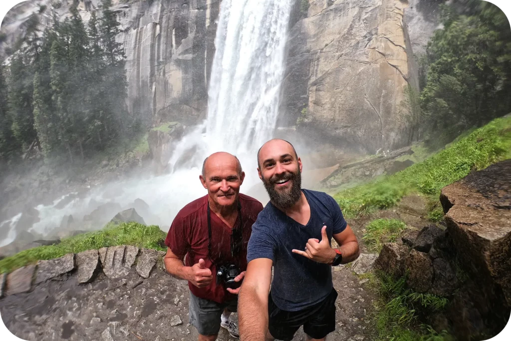Randonneurs souriants posant devant une impressionnante cascade au cœur d’un parc naturel, étape nature d’un itinéraire de voyage personnalisé entre aventure et grands espaces.
